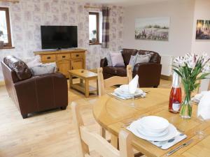 - un salon avec une table, des chaises et une télévision dans l'établissement Gardener's Lodge, à Nantwich
