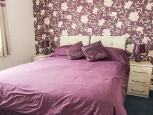 a bedroom with a purple bed with a floral wallpaper at Quarterdeck in Scarborough