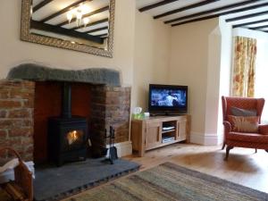 a living room with a fireplace and a tv at Greta Mill in Keswick