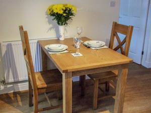 un tavolo di legno con due bicchieri e un vaso con fiori gialli di Oak Tree Cottage a Beverley