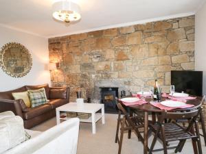 sala de estar con mesa y pared de piedra en Seascape, en Lossiemouth