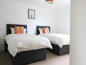インバネスにあるRowan Houseのベッドルーム1室(白とオレンジの枕が備わるベッド2台付)