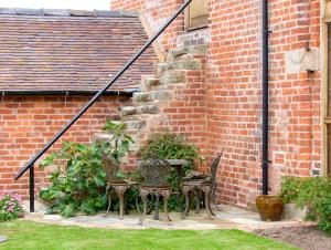 un patio con mesa y sillas junto a un edificio de ladrillo en The Coach House, en Shrewsbury