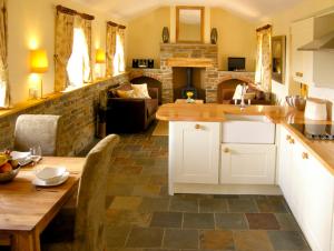 cocina con mesa de madera y pared de piedra en Valley View en Ross on Wye