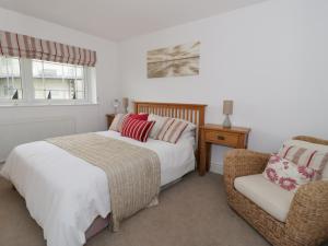 a bedroom with two beds and a chair at The Bungalow in Pwllheli