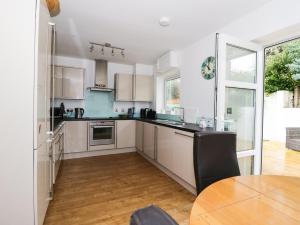 a kitchen with white cabinets and a wooden table at The Bungalow in Pwllheli +10 photos