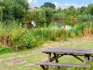 a wooden picnic table sitting in front of a lake at The Coach House in Shrewsbury
