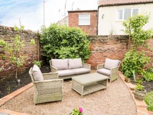 a patio with two chairs and a couch at October Cottage in Ripon