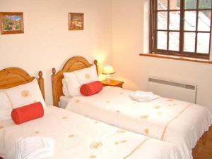 two twin beds in a bedroom with a window at Tailor's Cottage in Abbey-Cwmhir