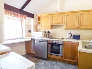 uma cozinha com armários de madeira e um aparelho branco em Parlour Cottage em Saint Erth