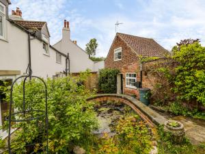 a stone house with a small bridge in a yard at October Cottage in Ripon