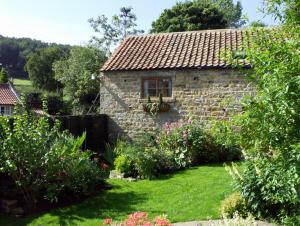 a stone house with a window and a garden at The Hayloft in Lastingham