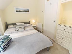 a white bedroom with a bed and a dresser at Cobble Cottage in Hornsea