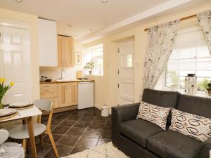 a living room with a couch and a kitchen at October Cottage in Ripon