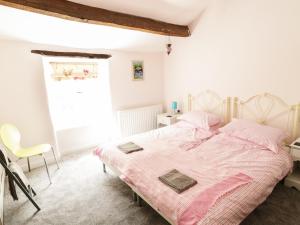 a bedroom with a large bed with pink sheets at Orchard Cottage in Lothersdale