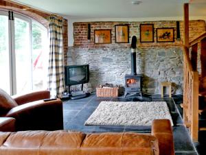 a living room with a couch and a stone wall at Glan Clwyd Isa - The Coach House in Denbigh
