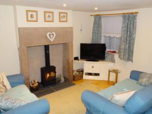 uma sala de estar com lareira e sofás azuis em Bobbin Cottage em Matlock
