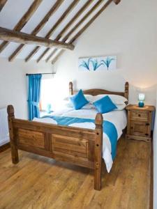 een slaapkamer met een houten bed met blauwe kussens bij Beudy Bach in Abergele