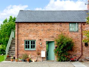 a brick house with a green door and stairs at Glan Clwyd Isa - The Coach House in Denbigh