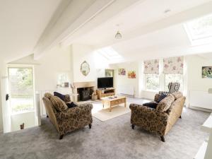 a living room with two chairs and a television at Orchard Cottage in Lothersdale