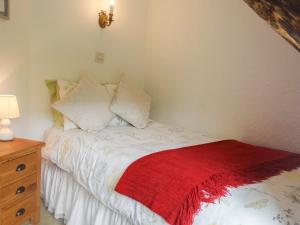 a bedroom with a bed with a red blanket on it at Little Thatch in Cerne Abbas