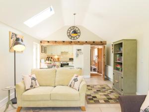 a living room with a couch and a kitchen at Stable Cottage in Tenbury