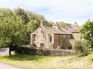 an old stone house with a stone wall at Orchard Cottage in Lothersdale