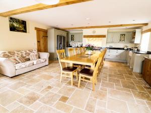 cocina y sala de estar con mesa de madera y sillas en The Hayloft en Knighton