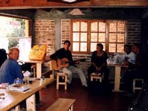 a group of people sitting in a room playing guitar at Puma Hostel in San Martín de los Andes