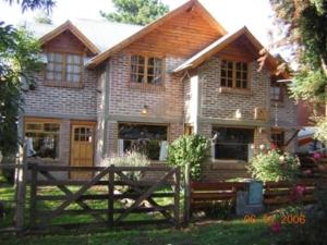 a house with a wooden fence in front of it at Puma Hostel in San Martín de los Andes