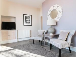 a living room with two chairs and a table and a mirror at Wye View in Ross on Wye