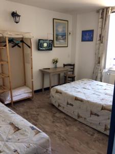 1 dormitorio con 2 camas, mesa y escritorio en Hôtel de la Gare, en Saint-Malo