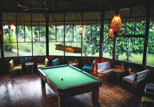 a room with a pool table and chairs and windows at Corto Maltes Amazonia Lodge in Puerto Maldonado
