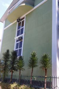 a green building with palm trees in front of it at Guesthouse Tatyiana in Sochi