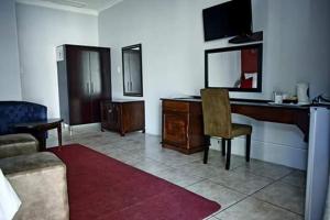 a living room with a desk and a chair at Ehrlichpark Lodge self catering and spa in Bloemfontein