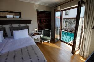a bedroom with a bed and a chair and a window at Akanthus Hotel Ephesus in Selcuk