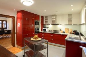 une cuisine avec des placards rouges et une table avec une plaque de cuisson. dans l'établissement KAYSERSBERG city center - House "AUX 7 FORGERONS" -, à Kaysersberg
