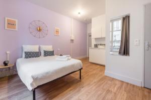 - une chambre blanche avec un grand lit et une cuisine dans l'établissement Apartments WS Hôtel de Ville - Musée Pompidou, à Paris