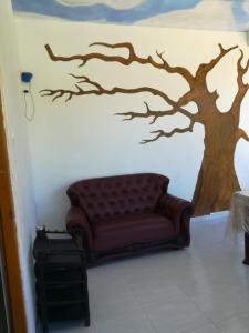 a couch in a room with a tree painted on the wall at White Arcadia cottage in Ella