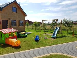 un parque infantil con tobogán y columpio en Ferienhäuser Eurobaltyk, en Rewal 17 fotos más