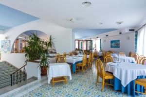 a restaurant with white tables and yellow chairs at Hotel Club Residence Martinica in Bonifati