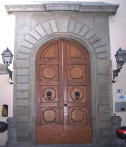 a large wooden door in a building with two lights at Hotel Aldobrandini in Florence