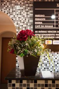 a vase with red roses sitting on top of a counter at Hotel Jardim América ( Adults only) in Sao Paulo