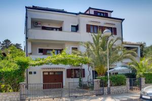 a white house with a palm tree in front of it at Argo Apartmani in Mali Lošinj