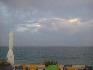 einen Strand mit einem geschlossenen Sonnenschirm und dem Meer in der Unterkunft Esperides Hotel in Paralia Agias Foteinis