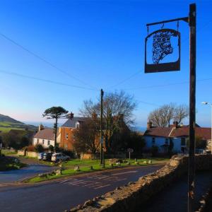 a street sign on a pole next to a street at King's Head Inn in Llangennith