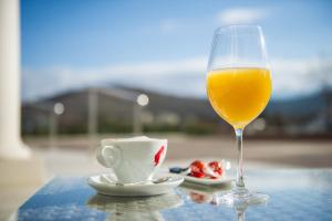 a glass of orange juice next to a cup and a teaucer at Hotel Jana in Međugorje