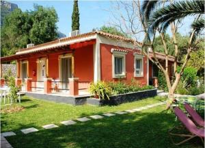 une maison rouge avec un palmier dans une cour dans l'établissement Bozikis Apartments & Studios, à Paleokastritsa