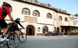 due persone in bicicletta di fronte a un edificio di Hotel Vinopa a Hustopeče