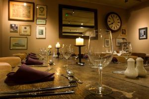 a table with wine glasses and a clock on the wall at The Punch Bowl Inn in Feetham
